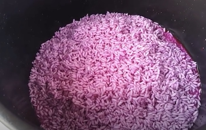 Cho gạo đã ngâm vào nồi và chuẩn bị đong nước nấu xôi lá cẩm